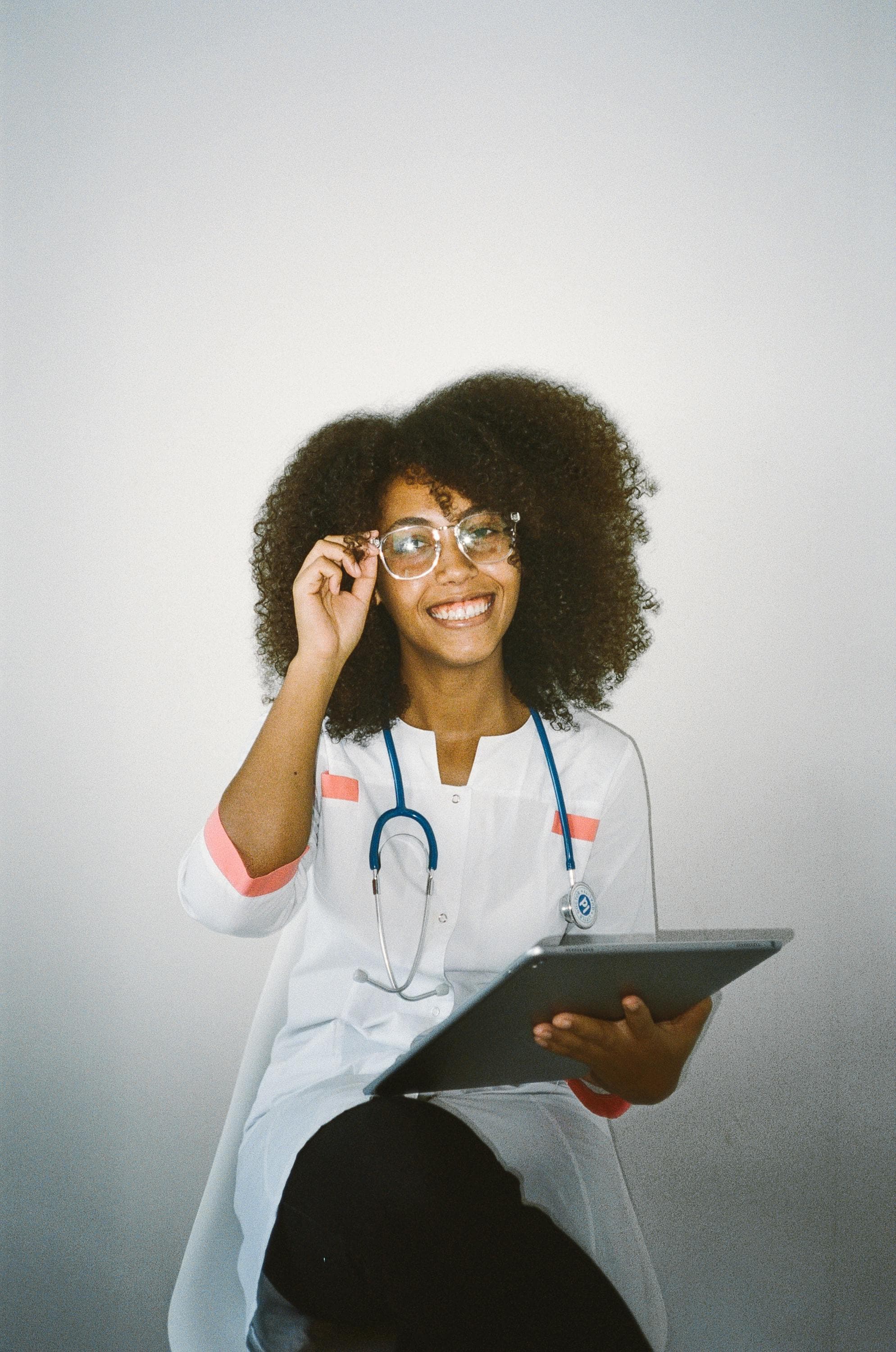 Confident young nurse with glasses and a stethoscope, holding a tablet