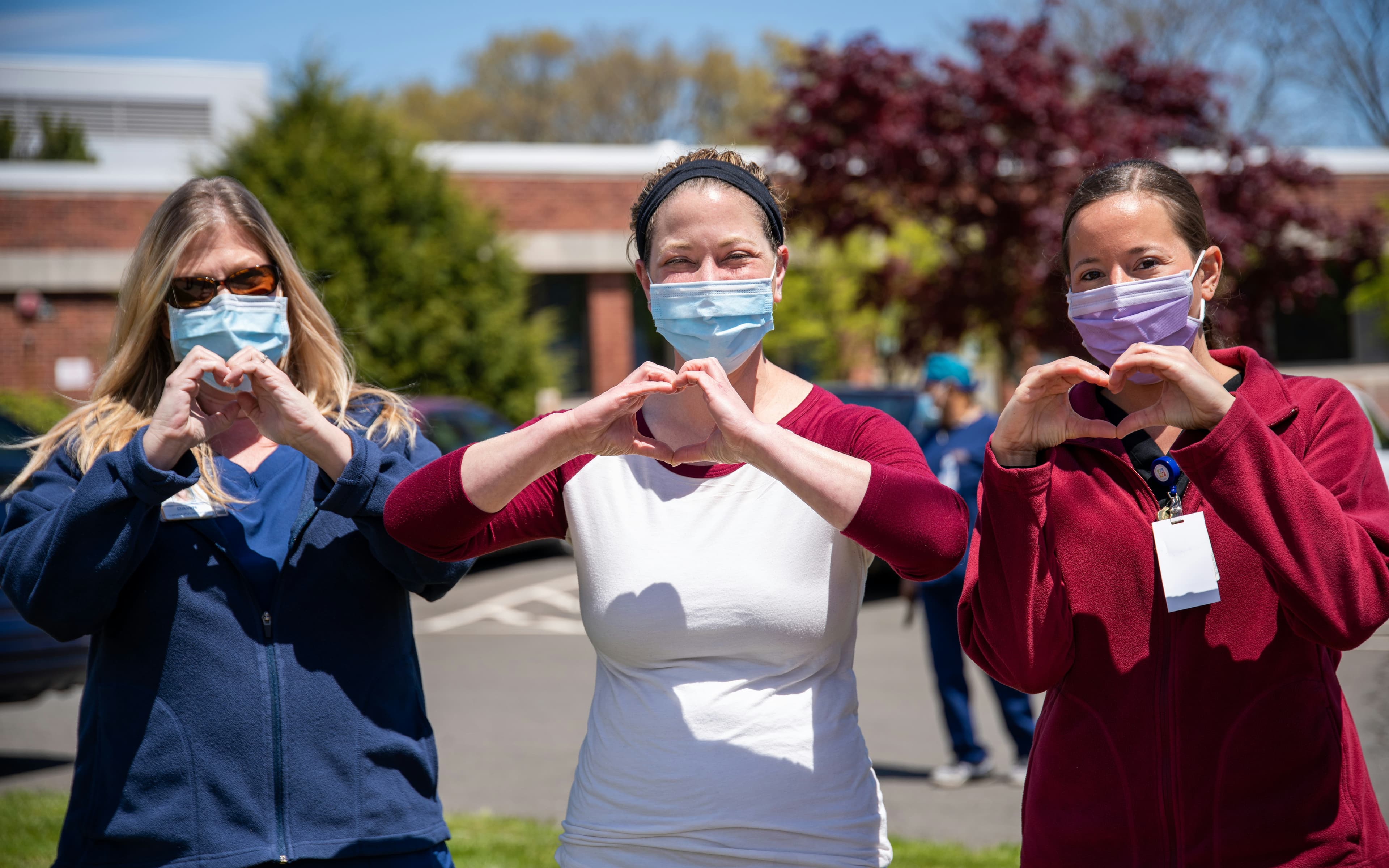 Nurses outside making heart shapes with their hands